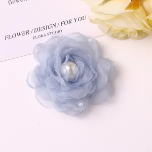 Close-up of light blue mesh fabric camellia flower with faux pearls for DIY crafts and accessories.