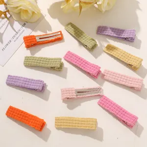 Detailed shot of colorful knitted fabric duckbill hair clips neatly arranged on a white surface.