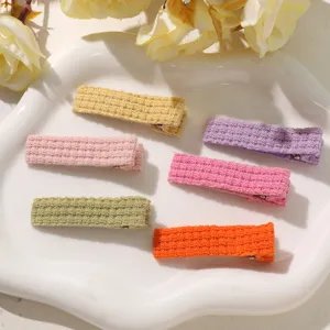 Close-up view of vibrant knitted hair clips in assorted candy colors displayed on a white tray.