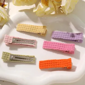 Colorful knitted hair clips detail shot, showcasing sweet candy colors and textured fabric surface.
