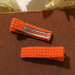 Close up view of orange knitted wool hair clip, sweet style side clip for children.