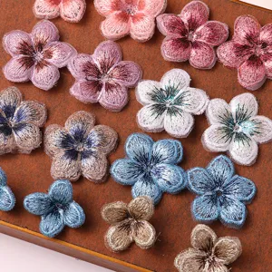 Close-up detail of vintage embroidered five-petal flower patches, gradient thread texture.