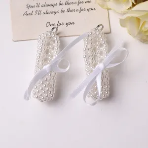Detailed close-up of handmade pearl beaded ballet flat shoe pendant with elegant white ribbon bow.