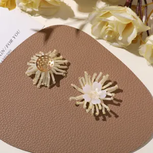 Detailansicht von DIY Perlen Blumen Anhänger Zubehör in Weiß und Gold Farbtönen.