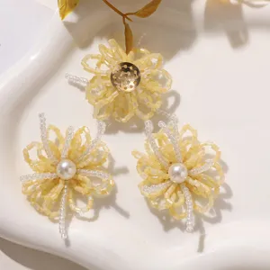 Detalle de flores de cuentas hechas a mano con accesorios DIY amarillos y blancos para pendientes.