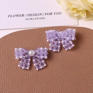 Detailed close-up of handmade purple beaded bow DIY accessories with pearl embellishment.