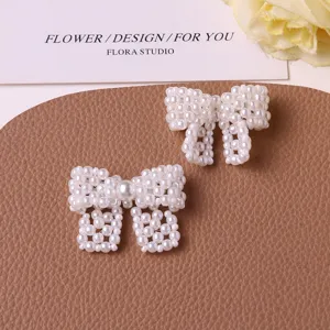 Close-up detail of white pearl beaded bow DIY accessories, elegant handmade craft decoration.