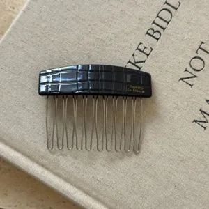 Détail peigne à cheveux texture crocodile noir, élégantes dents en métal accessoire acétate.