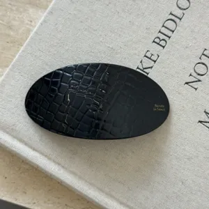 Pince à cheveux ovale noire texturée pour femme, barrette élégante en acétate pour coiffure.