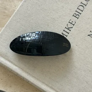 Barrette à cheveux ovale noire avec motif croco texturé, accessoire élégant pour coiffure.