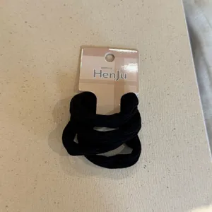 Close-up detail view of black elastic hair ties set with branded packaging card.