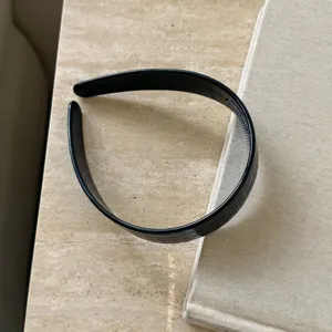 Vue détaillée du serre-tête noir, accessoire de coiffure minimaliste pour femmes.