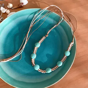 Bohemian turquoise beaded braided rope necklace detail, ethnic style jewelry closeup view.