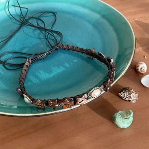 Detailed shot of bohemian style braided rope necklace with wooden star beads and pearl charm.