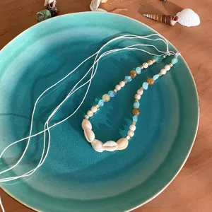 Detail shot of bohemian shell and stone braided rope jewelry, featuring natural cowrie and beads.