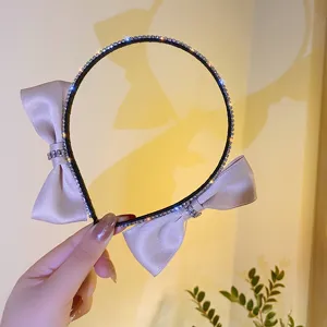 Close-up detail of rhinestone embellished headband with elegant satin bows on both sides.