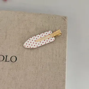 Cute red polka dot hair clip detail, stylish minimalist hair accessory for daily wear.