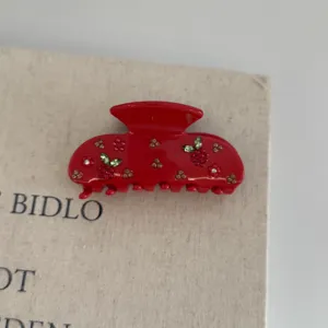 Red rhinestone hair claw clip detail shot, elegant berry design shark clip for women styling.