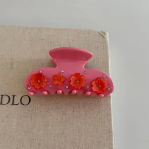 Pink resin floral hair claw clip detail, elegant sparkling rhinestone accent, secure grip hair accessory.