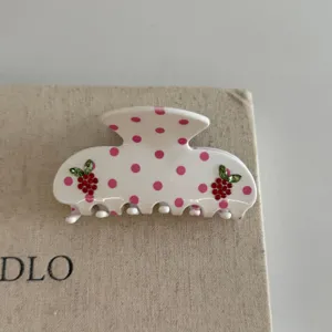 Sweet pink polka dot hair claw clip with crystal strawberry details for cute hairstyles.