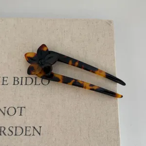 Tortoiseshell U-shaped hair fork detail, elegant floral accent for chic bun styling.