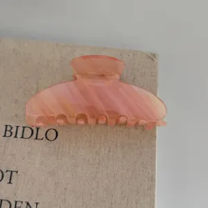 Close-up detail view of a large pink marbled hair claw clip, elegant styling accessory.