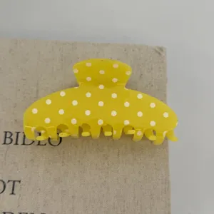 Yellow polka dot hair claw clip detail shot, cute resin hair accessory for daily styling.
