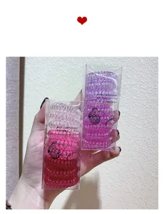 Close-up detail of colorful spiral hair ties in transparent boxes, showing elastic texture.