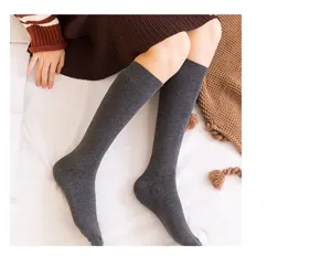 Detailed shot of dark grey knit tube socks styled on legs with cozy blanket background.