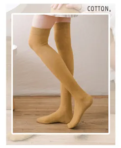 Nahaufnahme von senfgelben Overknee-Socken, weicher Baumwollstoff, kuschelige Alltagskleidung.