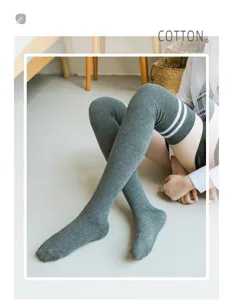 Dettaglio calze alte in cotone grigio, gambaletti lunghi con strisce bianche casuali.