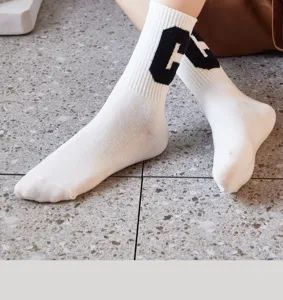 Calzini bianchi da donna con lettera C lavorata a maglia nera per un look alla moda.