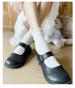 Primo piano dettagliato di calzini bianchi di pizzo abbinati a scarpe nere classiche.
