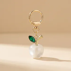 Elegant acrylic pearl apple keychain with green crystal leaf and gold clasp for bags.