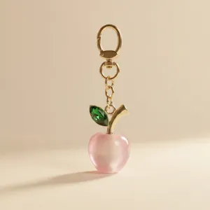 Elegant pink apple keychain with gold chain and green crystal leaf charm for women bags.
