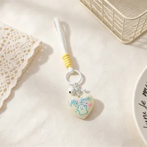 Cute ghost heart keychain detail showing resin pendant, white lanyard, and metal bell charm.