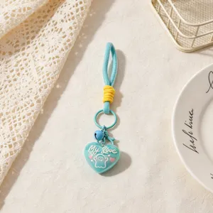 Close up of a cute blue heart keychain with strap and bell, ideal bag charm accessory.