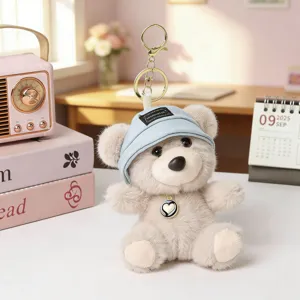 Cute plush bear keychain bag charm with mini hat and heart pendant, detailed view shot.
