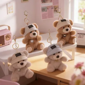 Cute plush bear keychain with hat and heart pendant, soft bag charm toy for women and girls.