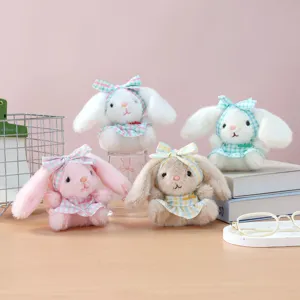 Detailed shot of cute plush rabbit doll pendants with plaid bows and dresses for bags.