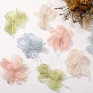 Detailed view of handmade fabric camellia hair clips with delicate pearl chains and petals.
