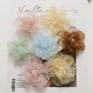 Detailed view of handmade sheer organza flower accessories with pearl center in multi colors.