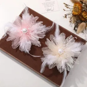 Dettaglio ravvicinato dell'accessorio per capelli a fiore in tulle con piume e perle.