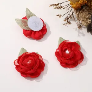 Detailed view of red mesh rose flower DIY hair accessory with pearl center and green leaves.