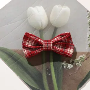 Close-up detail of red plaid fabric bow hair clip, cute preppy vintage hair accessory.