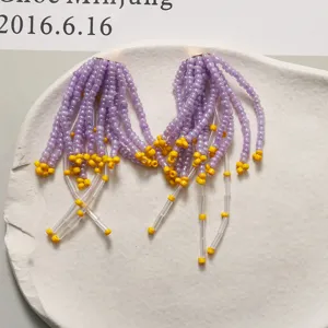 Dettaglio accessorio con frange di perline fatte a mano, design a cascata viola e giallo.