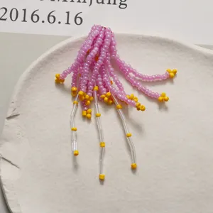 Dettaglio nappa di perline fatta a mano, rocaille rosa e gialle per creazione di gioielli.