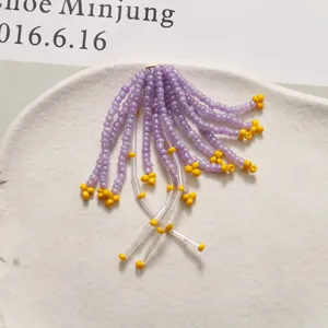 Dettaglio di nappa di perline viola e gialle fatte a mano, delicato accessorio per gioielli DIY.