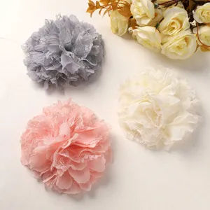 Primer plano de accesorios de flores de gasa y encaje DIY en gris, rosa y crema para manuales.