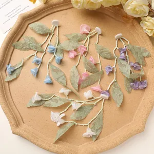 Detailed view of DIY handmade lace fabric flower and green leaf tassel earring accessories.